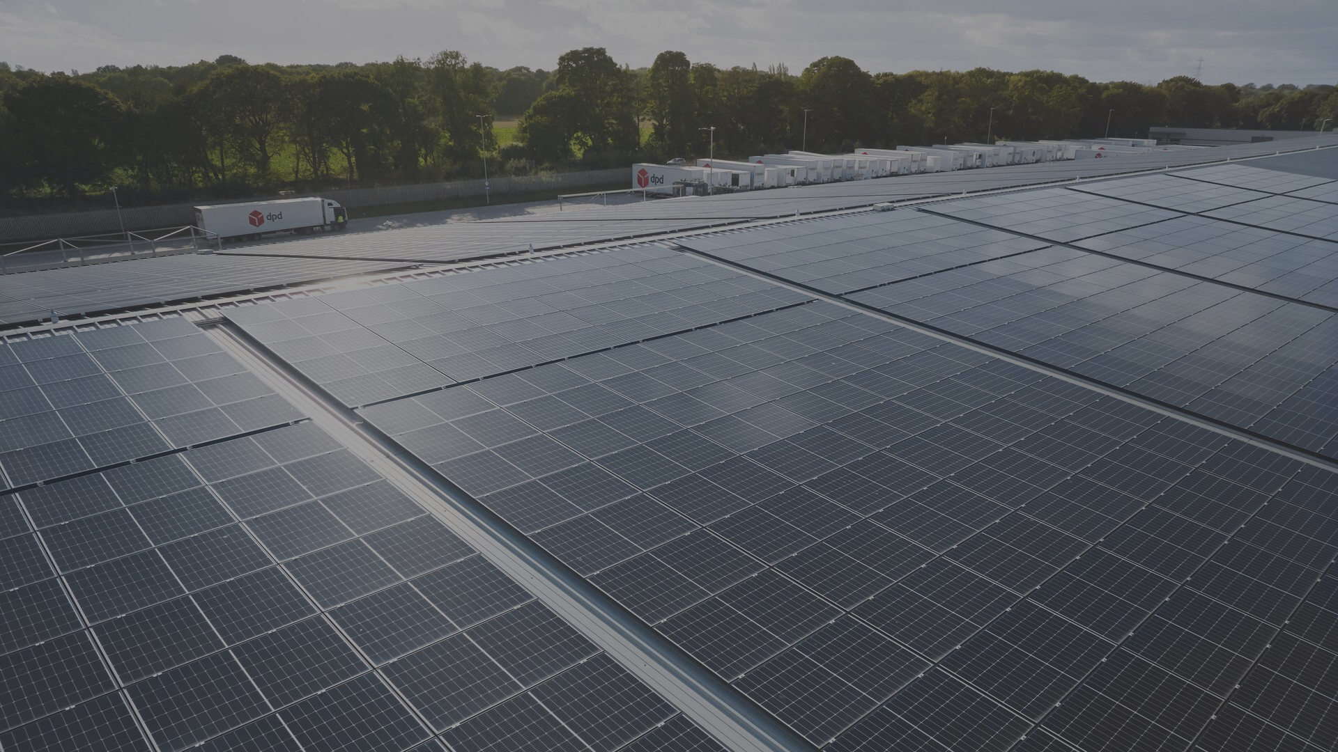 Photovoltaic panels on a hill with dpd vans in the background