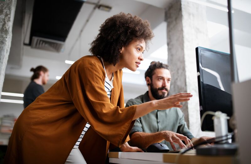 Two co-workers discussing in front of a computer